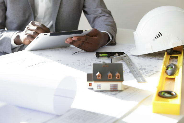 Expert en rénovation - Plan recadré d'un entrepreneur tenant une tablette tactile - faq - Prestations Professionnels