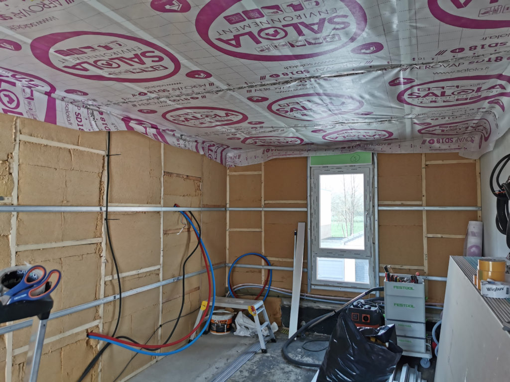 Pose d’un pare-vapeur sur l’isolation du plafond pour améliorer la performance énergétique.