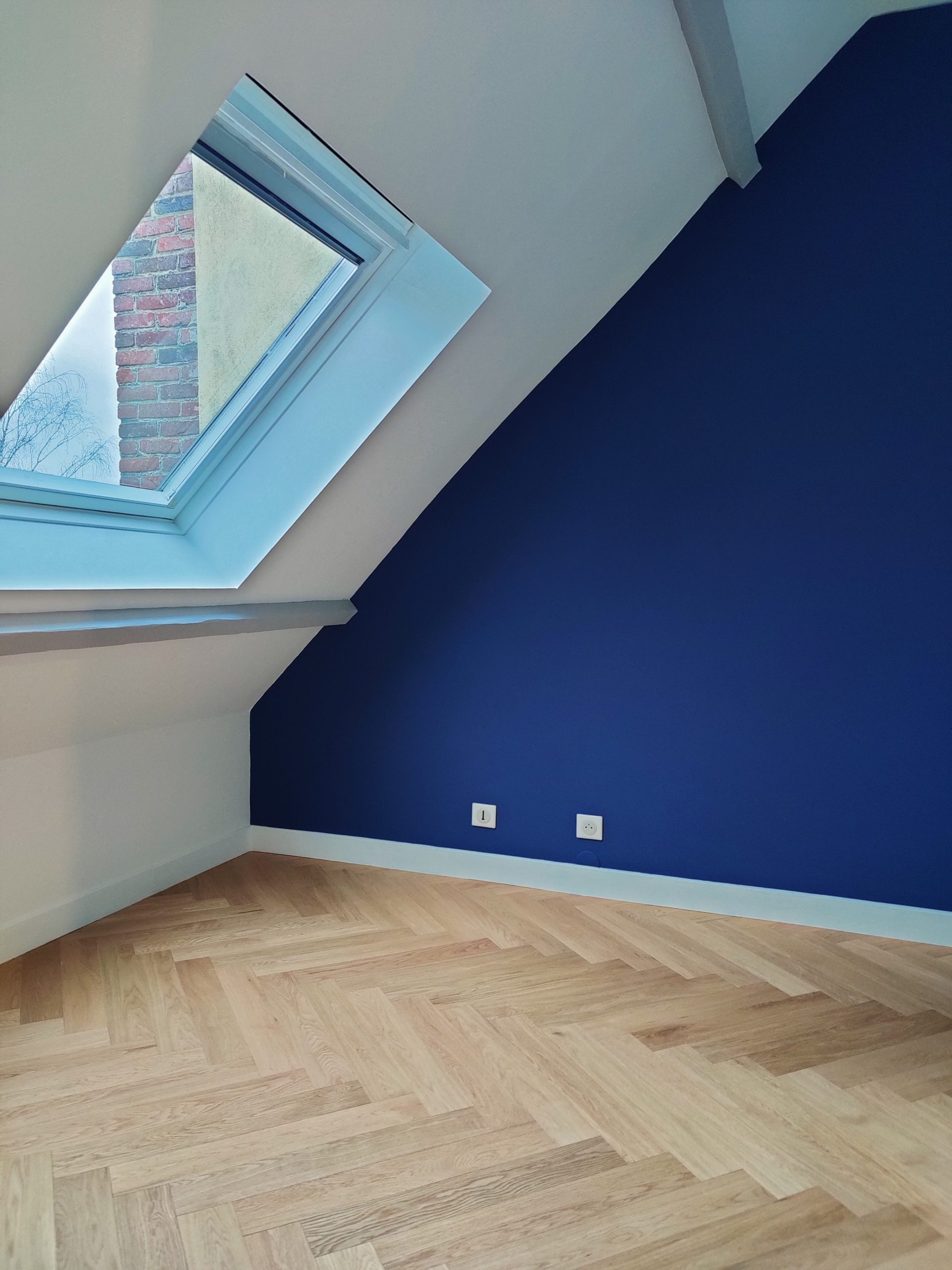 Réalisation de la peinture dans une chambre mansardée rénovée.