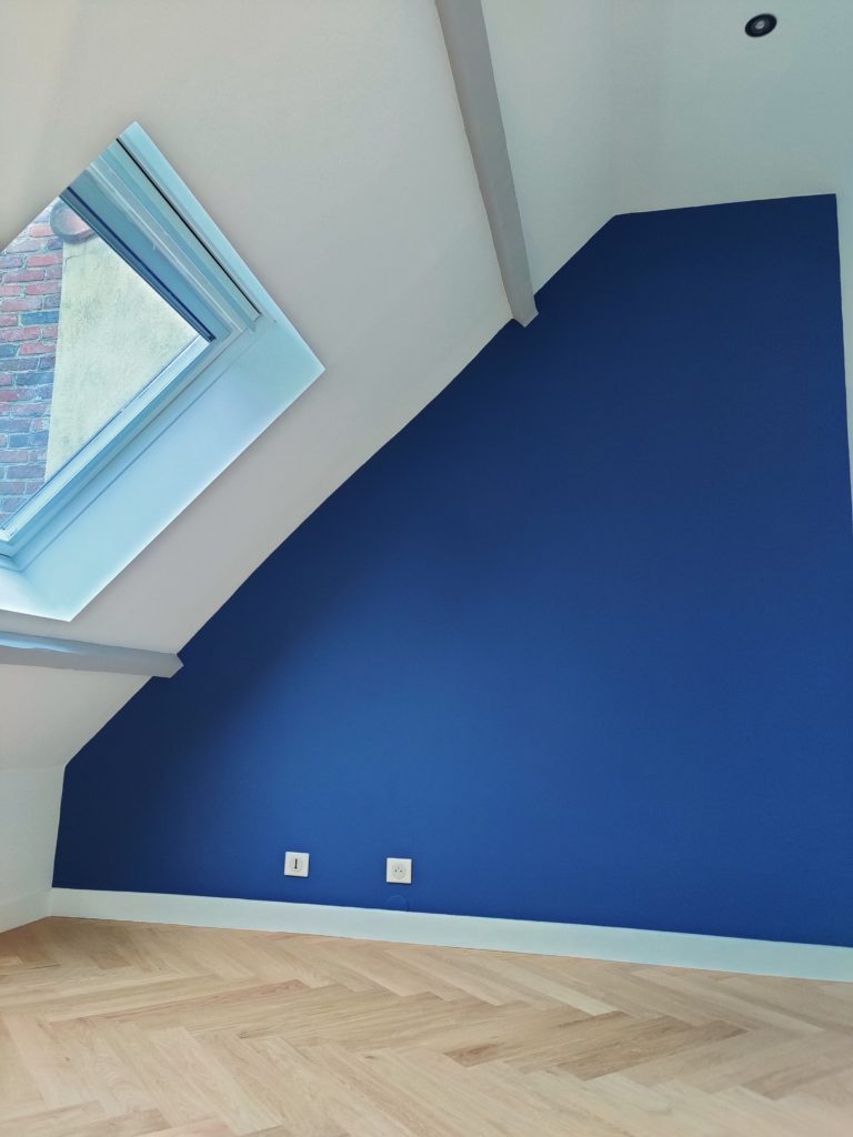 Finition soignée et pose de parquet dans une chambre mansardée rénovée.