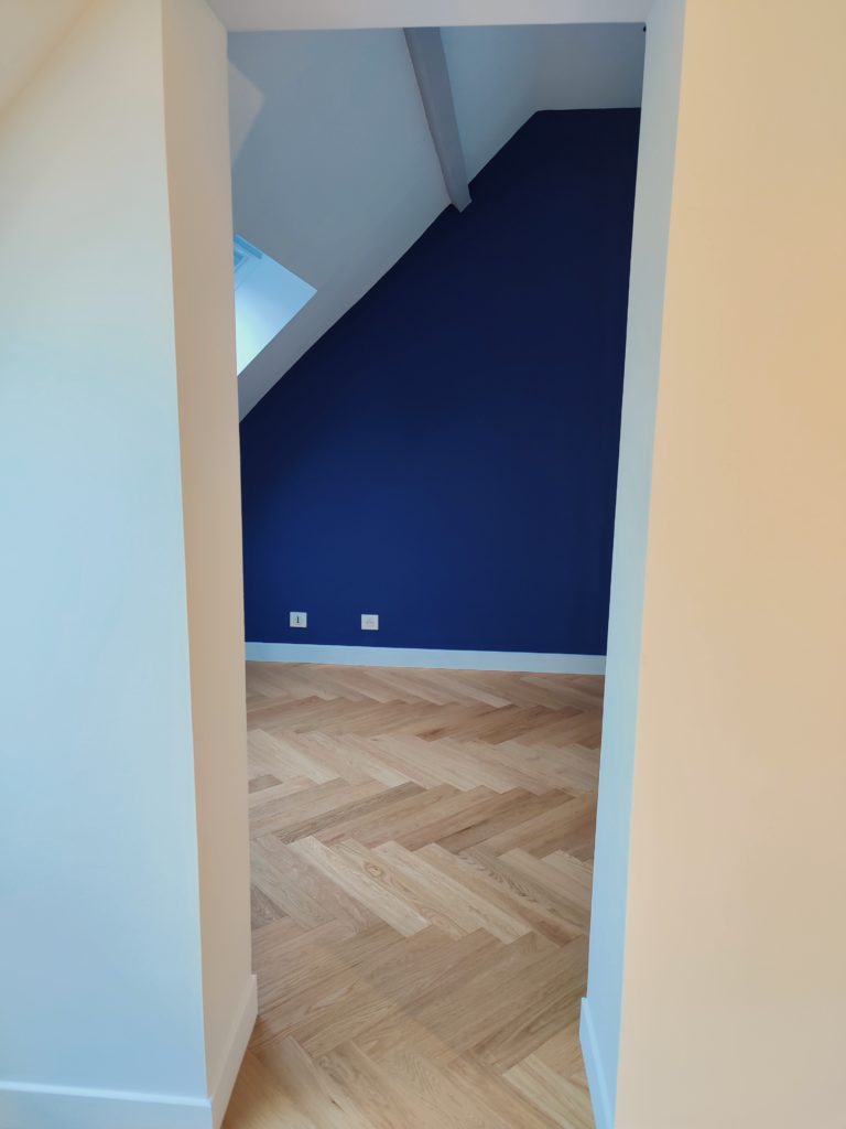 Travaux de peinture et finitions dans une chambre mansardée rénovée.