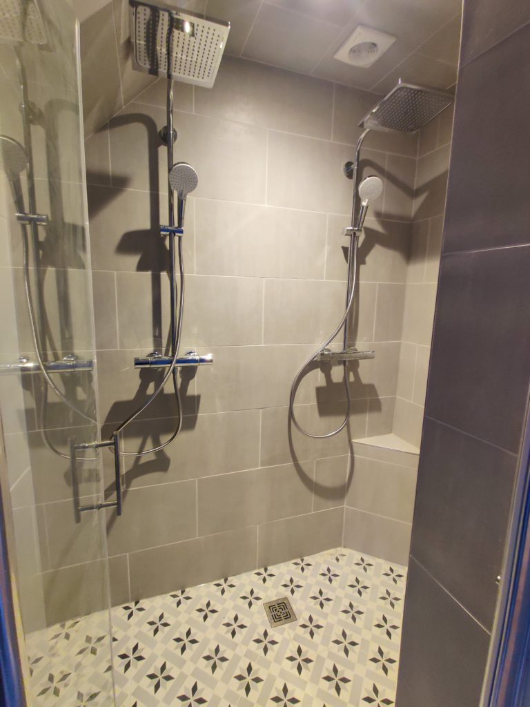Création d’une double douche avec grands carreaux muraux et receveur carrelé façon crédence de pays.