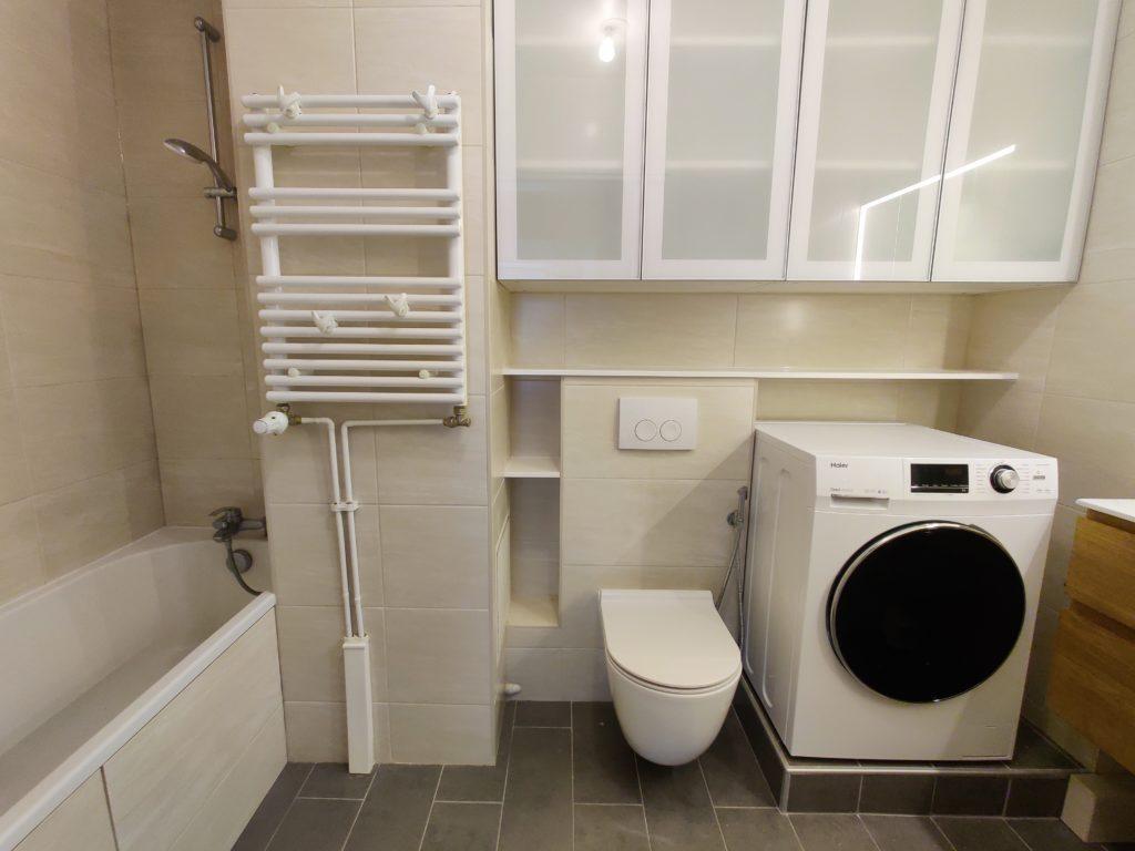 Installation d’un WC suspendu, d’une baignoire et d’un sèche-serviettes dans une salle de bains rénovée.