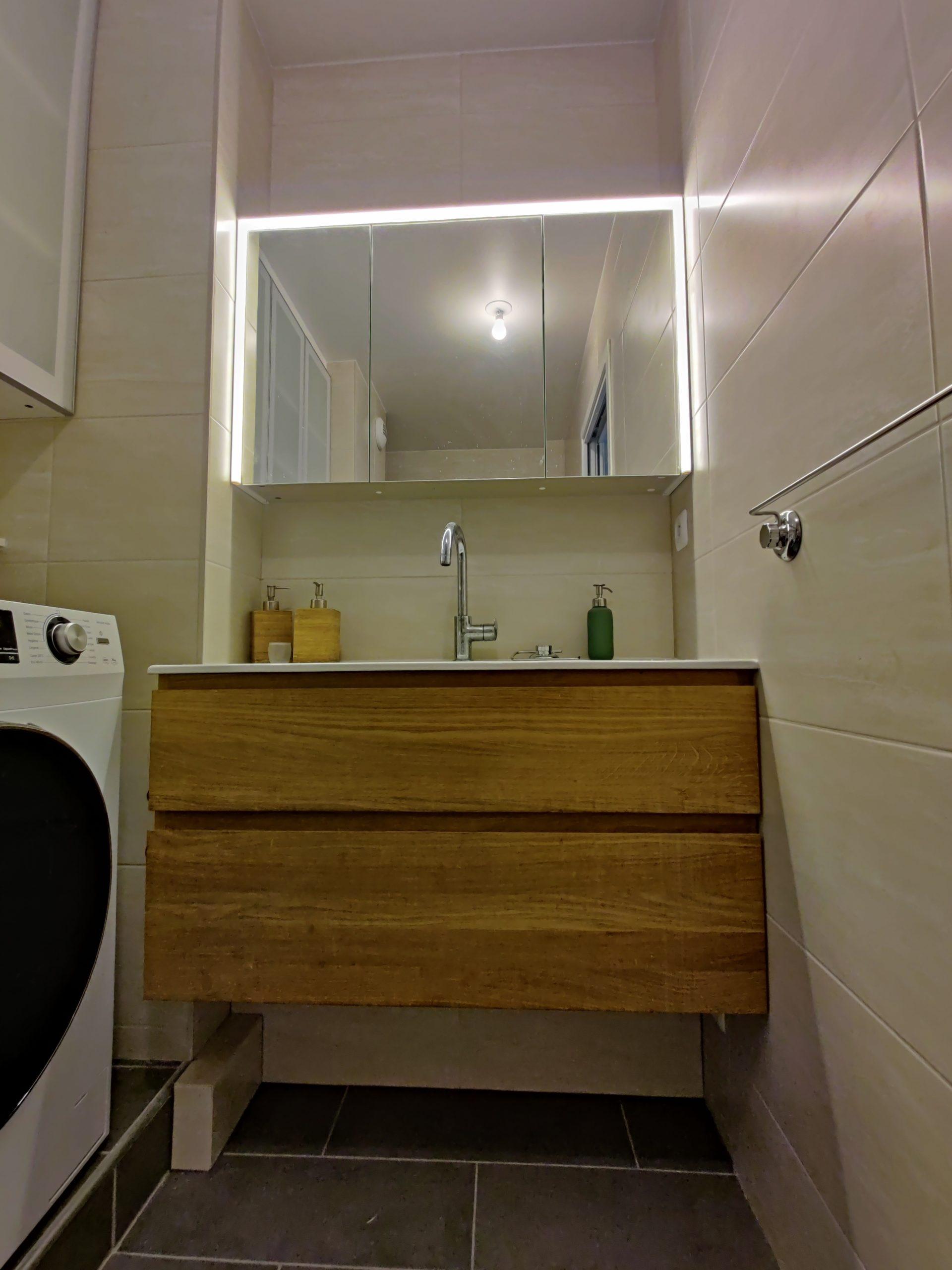 Pose d’un grand meuble avec vasque dans une salle de bains rénovée à Paris.