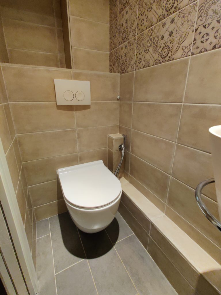 Aménagement mural avec installation de grands carreaux tout en longueur dans des WC rénovés.