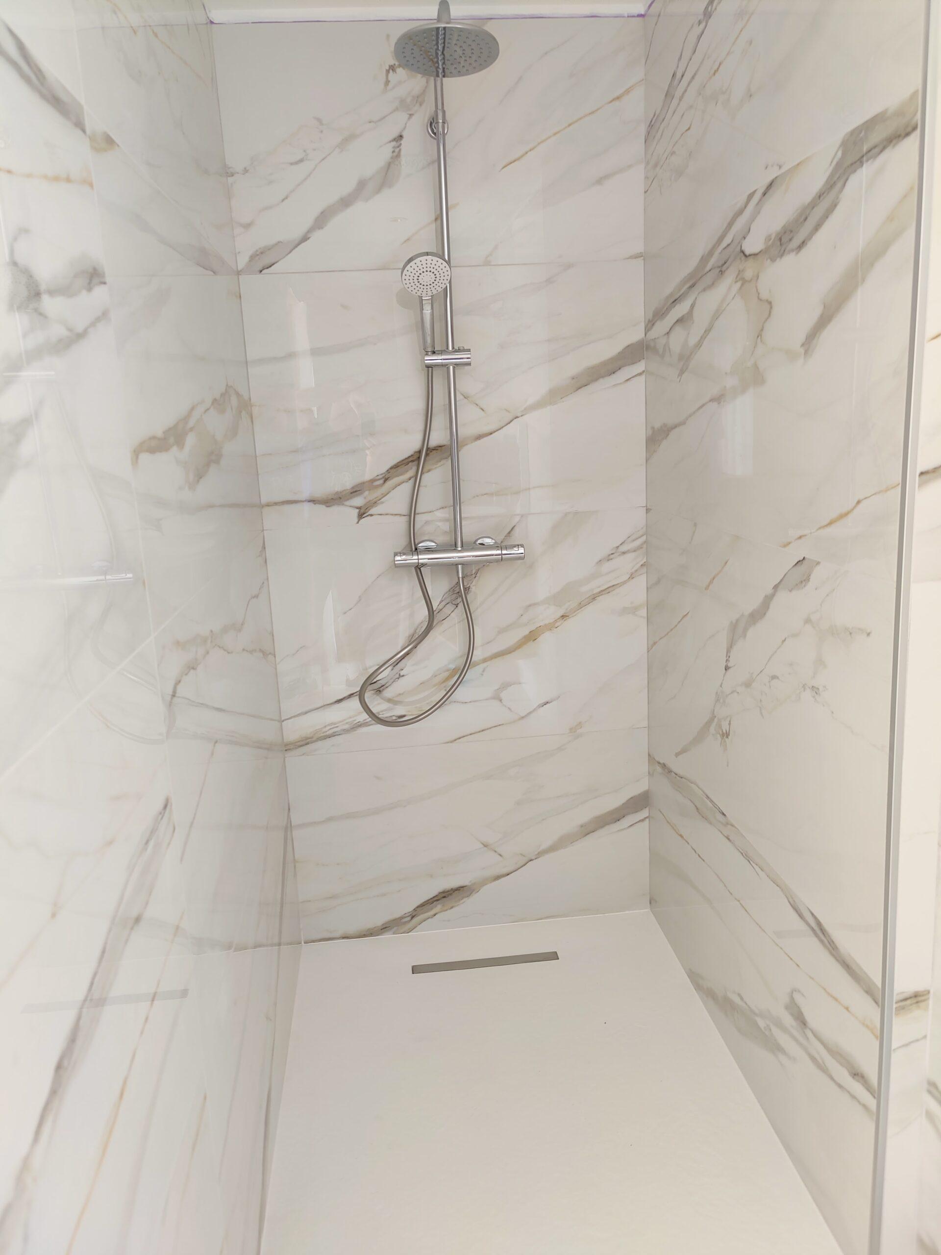 Création d’une douche élégante avec parement en marbre et installation d’une colonne de douche moderne.
