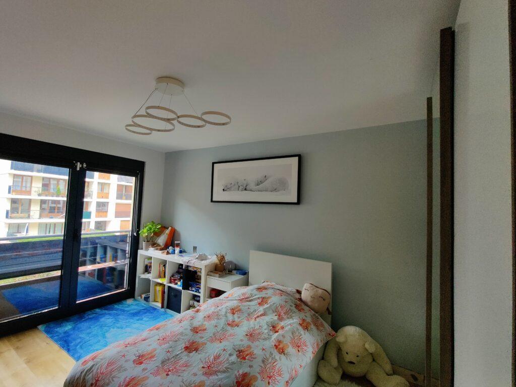 Rénovation complète d’une chambre parisienne avec peinture des murs et installation d’un luminaire au plafond.