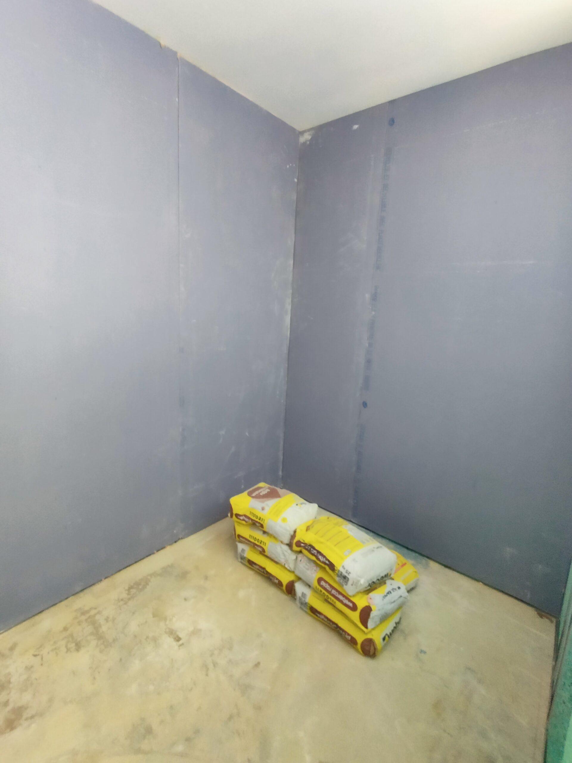 Lot de sacs de plâtre et de ciment dans une nouvelle salle en cours d’aménagement