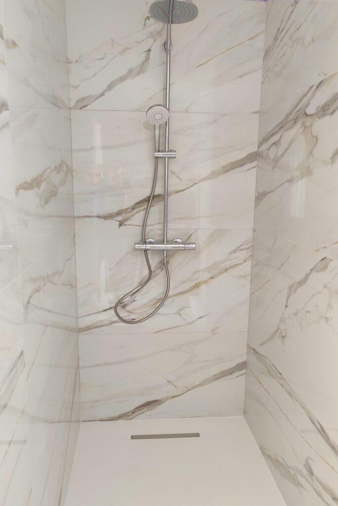 Une belle douche avec des parois en carrelage effet marbre