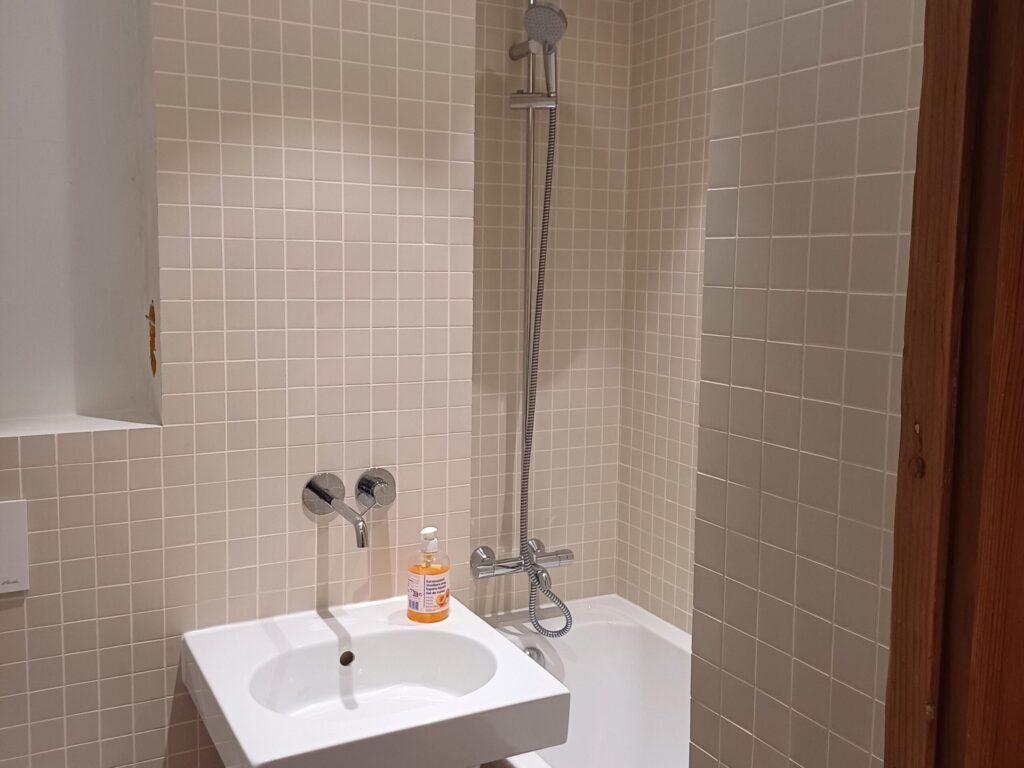 Salle de bain avec robinetterie moderne et faïence à petits carreaux beige