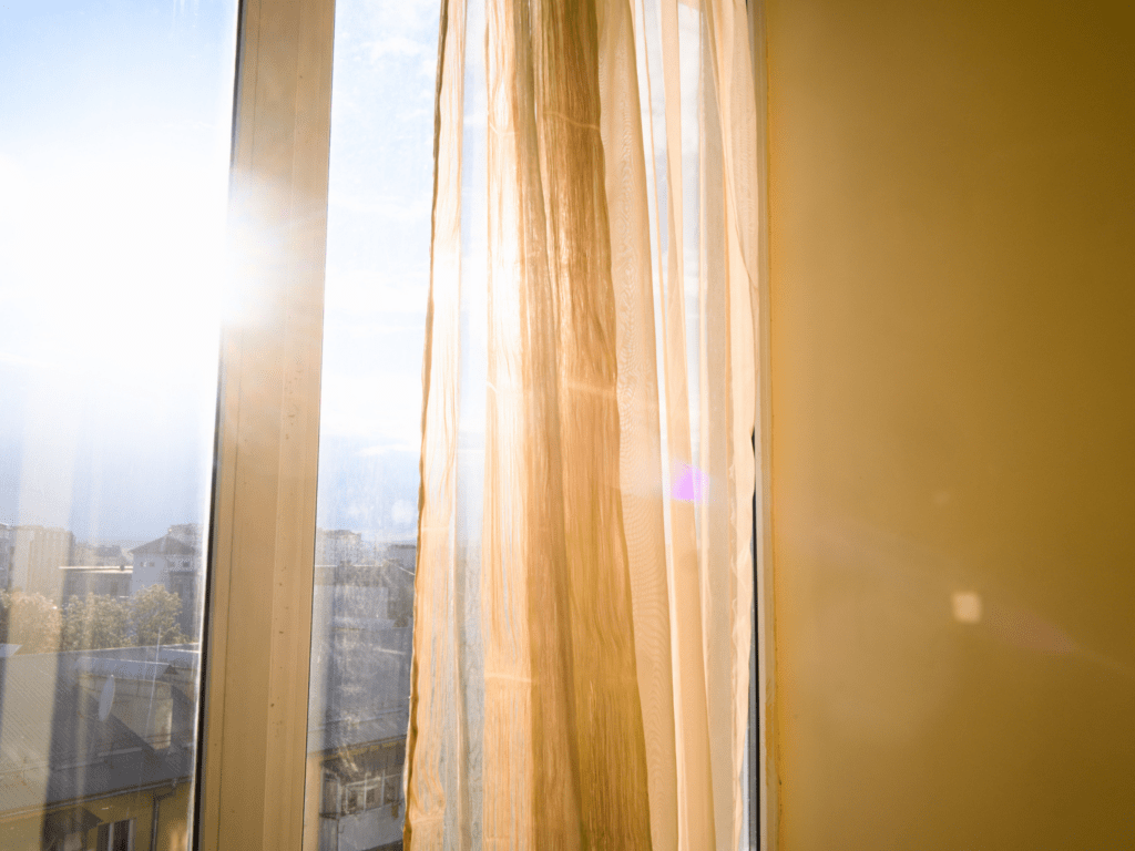 Rayons de soleil traversant un voilage à une fenêtre