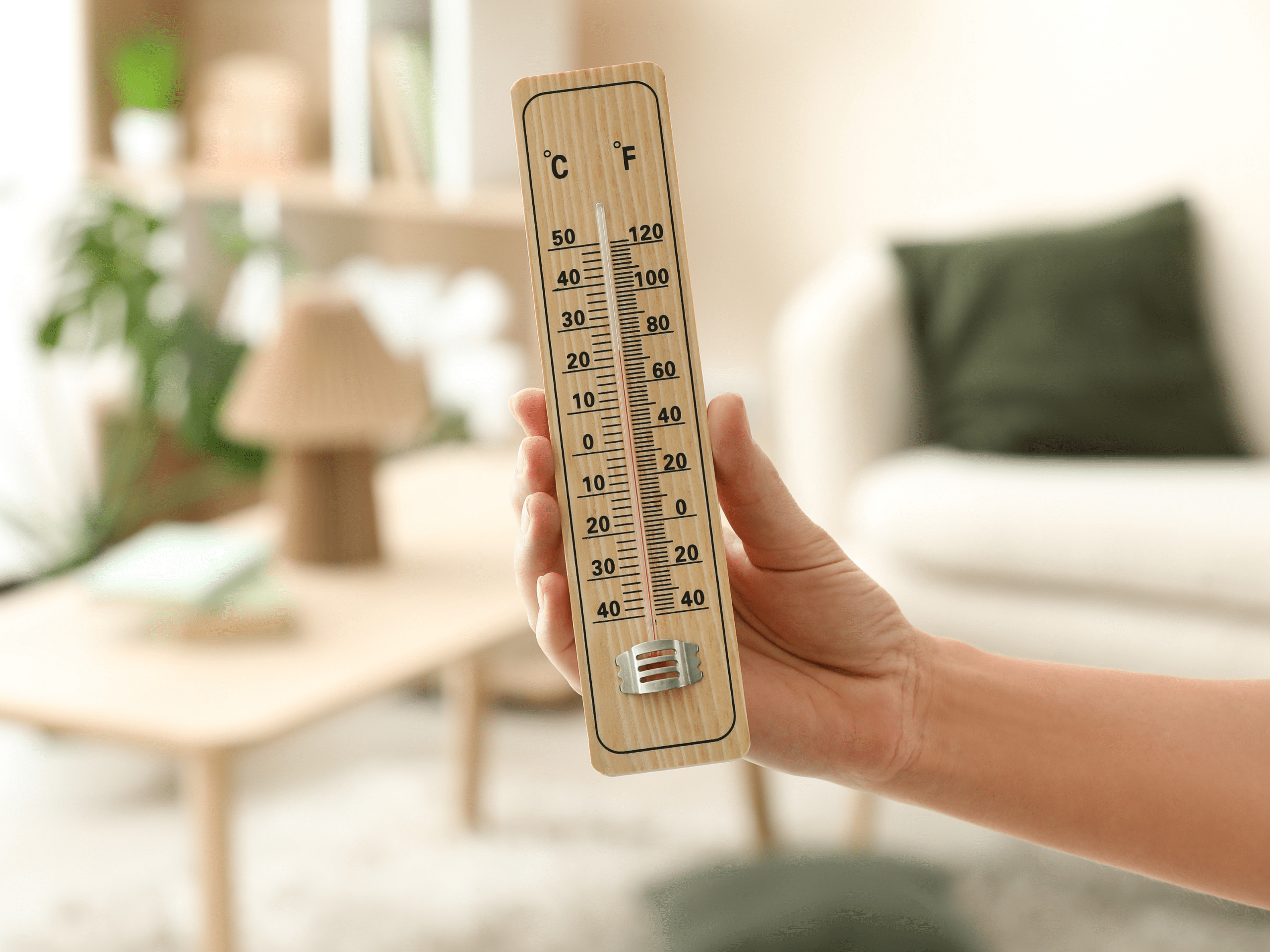 Main tenant un thermomètre d'intérieur en bois